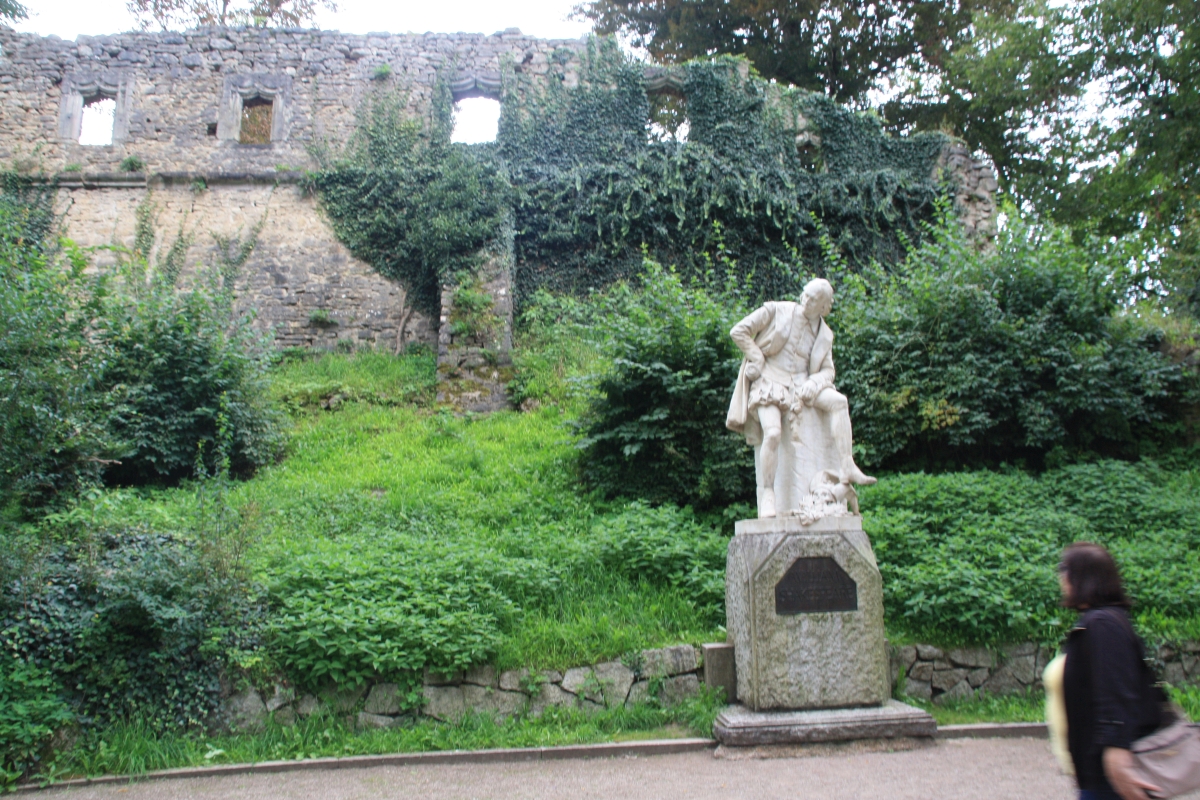 Denkmal von William Shakespeare vor einer künstlichen Ruine